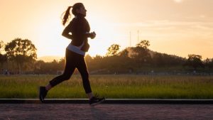 Woman running on track at sunset.
